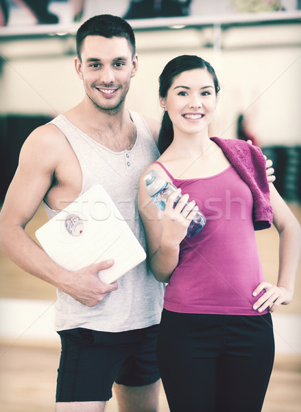 Stock photo: two smiling people with scale in the gym