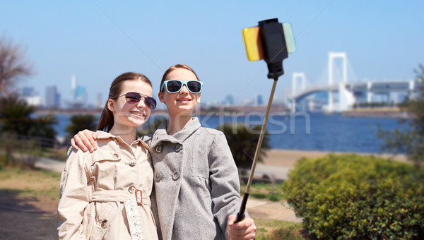 happy girls with smartphone selfie stick in tokyo Stock photo © dolgachov