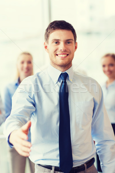 Stock photo: smiling businessman making handshake in office