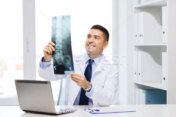 smiling male doctor in white coat looking at x-ray Stock photo © dolgachov