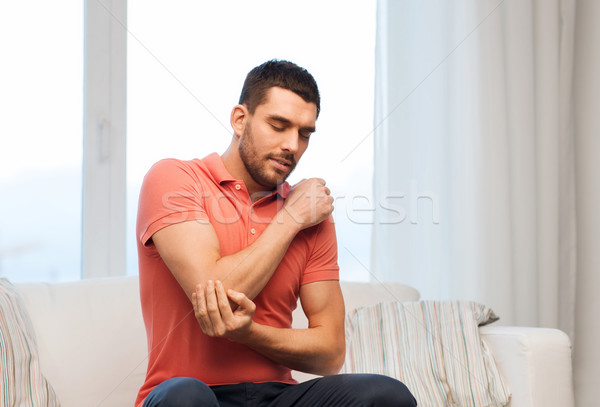 unhappy man suffering from pain in hand at home Stock photo © dolgachov