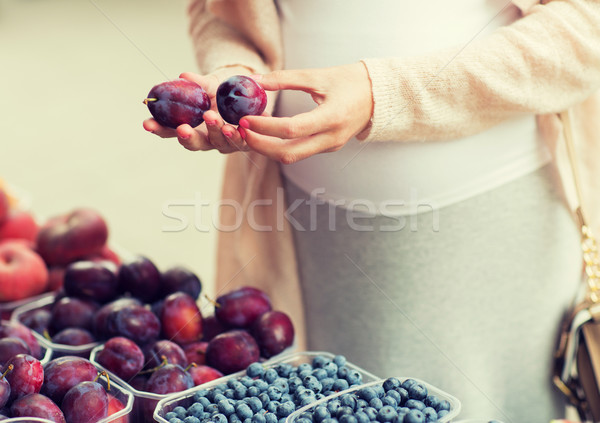 pregnant woman choosing plums at street market Stock photo © dolgachov