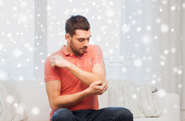 unhappy man suffering from pain in hand at home Stock photo © dolgachov