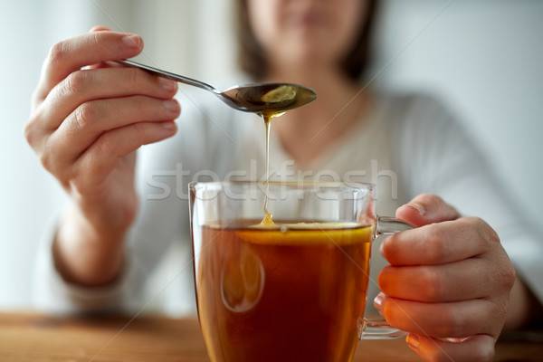 close up of woman adding honey to tea with lemon Stock photo © dolgachov