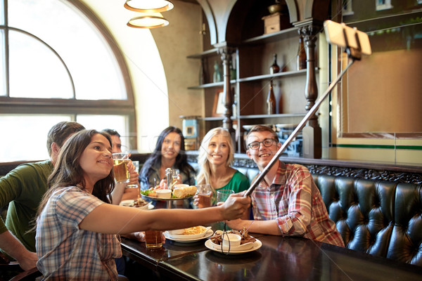 happy friends with selfie stick at bar or pub Stock photo © dolgachov