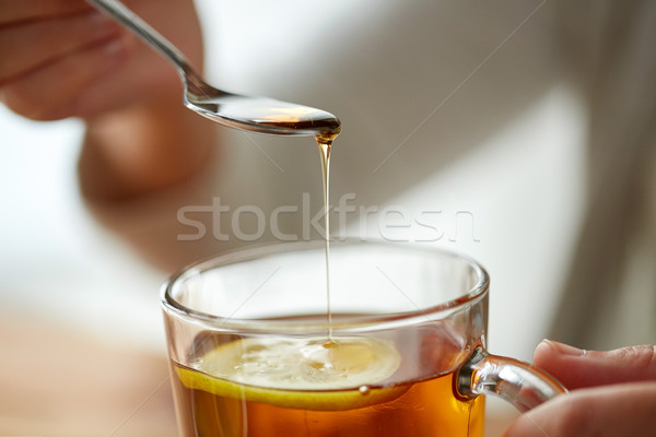 close up of woman adding honey to tea with lemon Stock photo © dolgachov