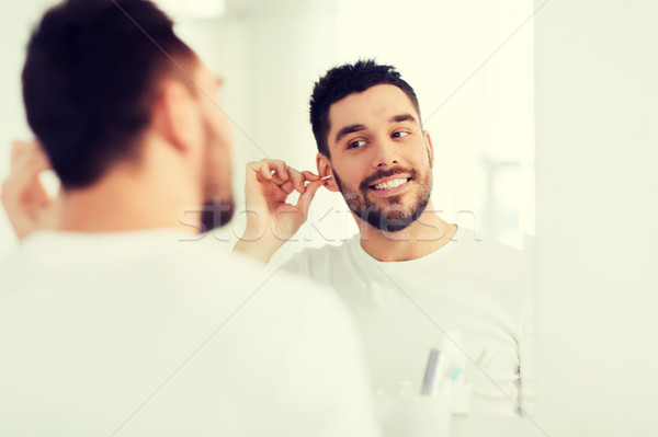 man cleaning ear with cotton swab at bathroom Stock photo © dolgachov