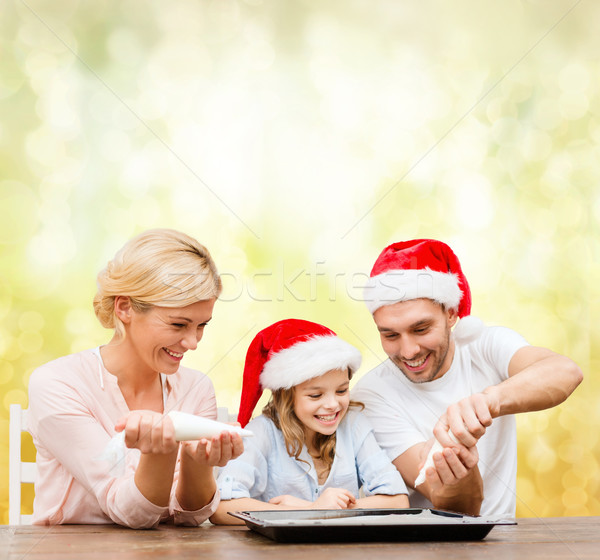 Stock photo: happy family in santa helper hats making cookies