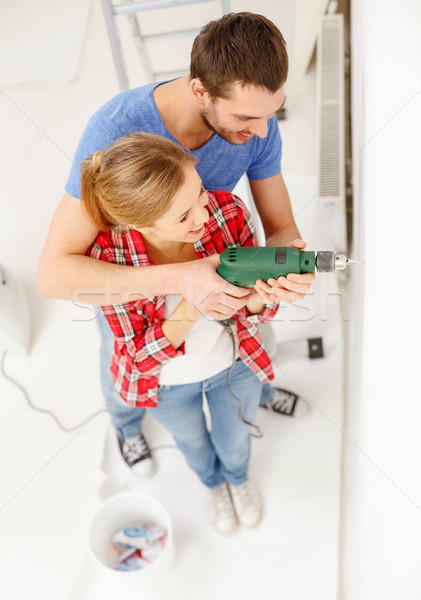 smiling couple drilling hole in wall at home Stock photo © dolgachov