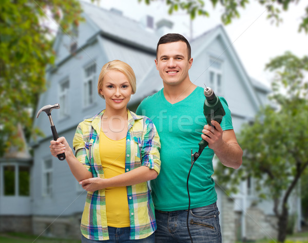 smiling couple with hammer and drill over house Stock photo © dolgachov