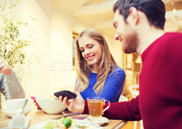 smiling couple with smartphones meeting at cafe Stock photo © dolgachov