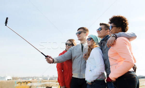 friends taking selfie with smartphone on stick Stock photo © dolgachov