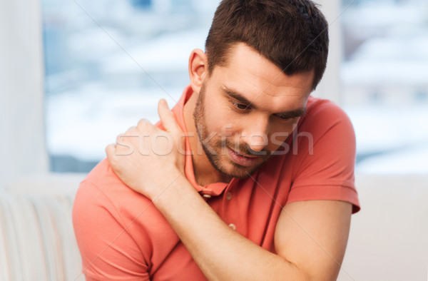 unhappy man suffering from neck pain at home Stock photo © dolgachov