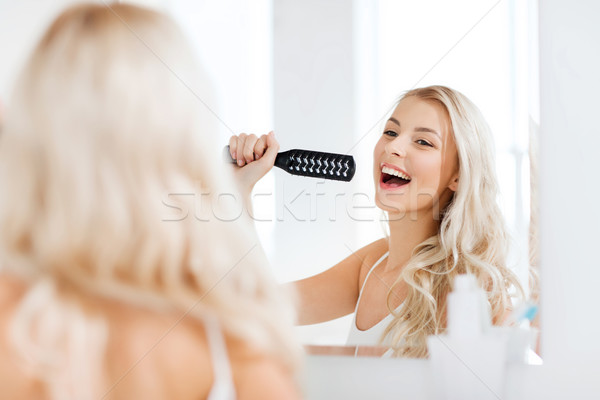 happy woman singing to hair brush at bathroom Stock photo © dolgachov