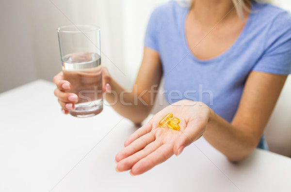 close up of woman hands with capsules and water Stock photo © dolgachov