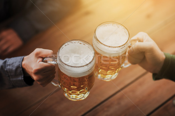 close up of hands with beer mugs at bar or pub Stock photo © dolgachov
