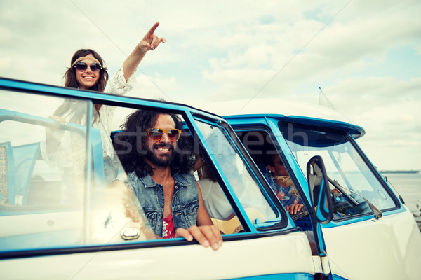 Stock photo: smiling young hippie friends over minivan car