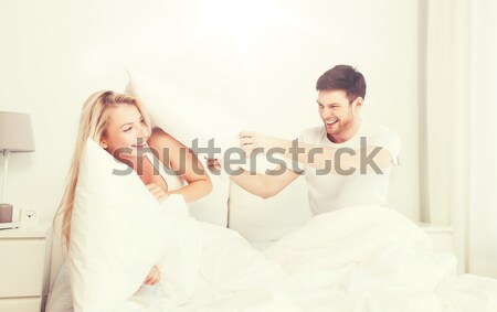 Heureux couple bataille d'oreillers lit maison personnes [[stock_photo]] © dolgachov