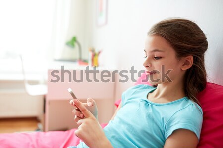 smiling girl texting on smartphone at home Stock photo © dolgachov