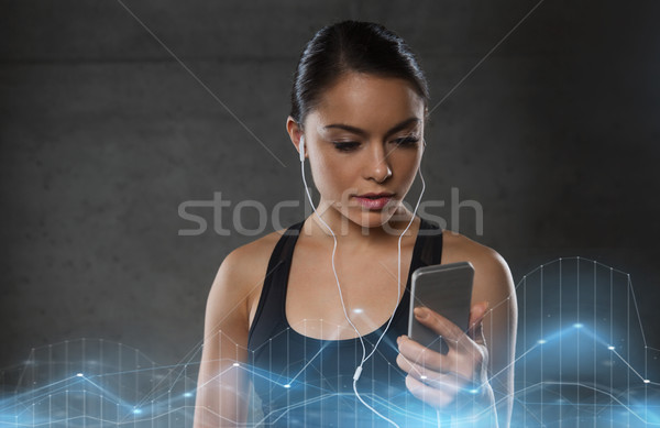 woman with smartphone and earphones in gym Stock photo © dolgachov