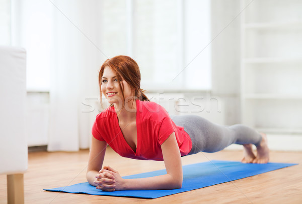 Stock photo: smiling redhead teenage girl doing plank at home