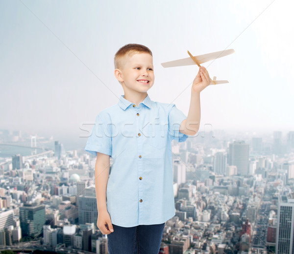 Stock photo: smiling little boy holding a wooden airplane model