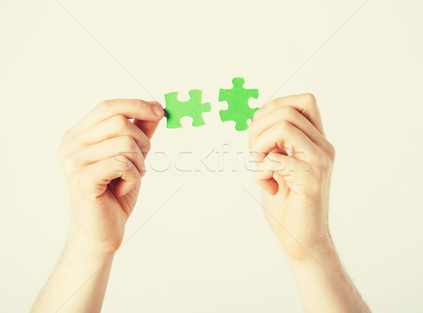 Stock photo: two hands trying to connect puzzle pieces