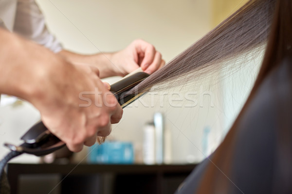 stylist with iron straightening hair at salon Stock photo © dolgachov