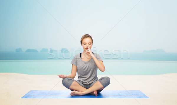 woman making yoga meditation in lotus pose on mat Stock photo © dolgachov