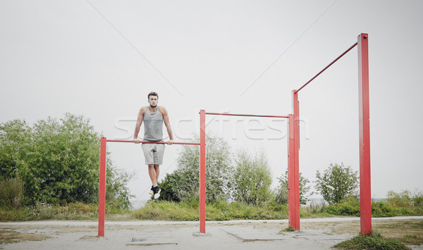 Stock photo: young man exercising on horizontal bar outdoors