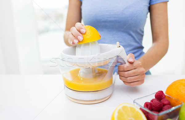 Stock photo: close up of woman squeezing fruit juice at home