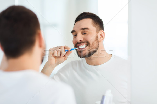 Homme brosse à dents nettoyage dents salle de bain [[stock_photo]] © dolgachov