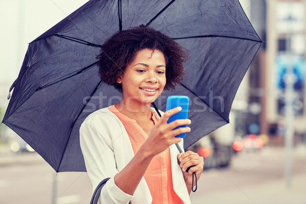 businesswoman with umbrella texting on smartphone Stock photo © dolgachov