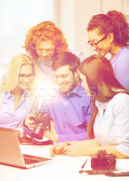 smiling team with laptop and photocamera in office Stock photo © dolgachov