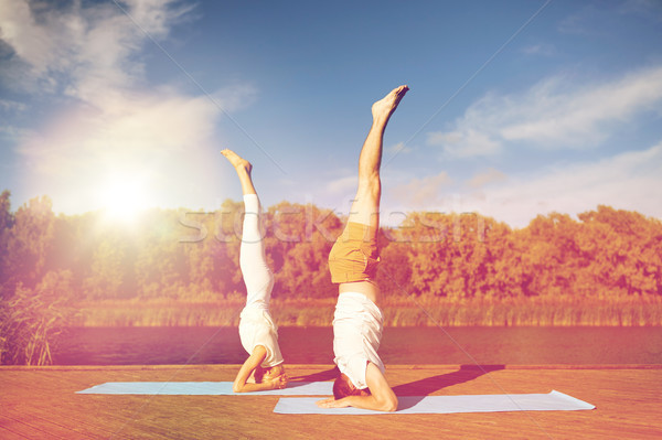 couple making yoga headstand on mat outdoors Stock photo © dolgachov