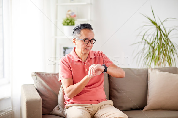 asian man checking time on wristwatch at home Stock photo © dolgachov