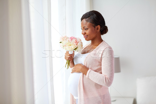 Stock photo: happy african american pregnant woman with flowers