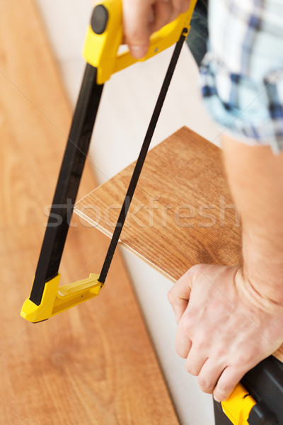 close up of male hands cutting parquet floor board Stock photo © dolgachov