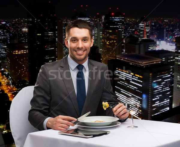 smiling man with tablet pc eating main course Stock photo © dolgachov