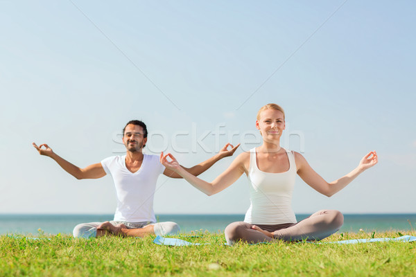 Glimlachend paar yoga buitenshuis fitness Stockfoto © dolgachov