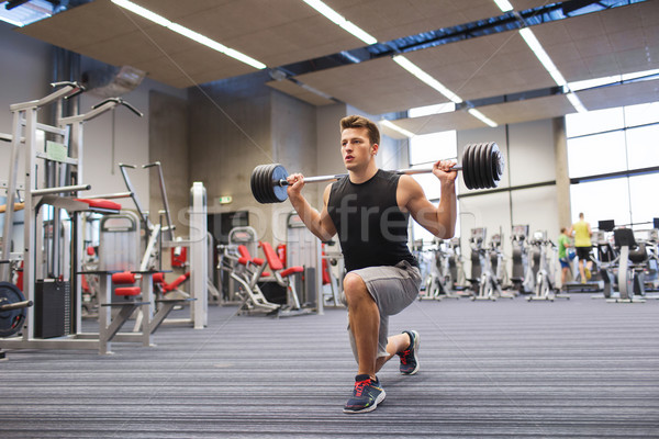 young man flexing muscles with barbell in gym Stock photo © dolgachov