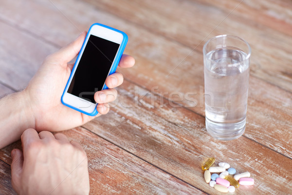 close up of hands with smartphone, pills and water Stock photo © dolgachov