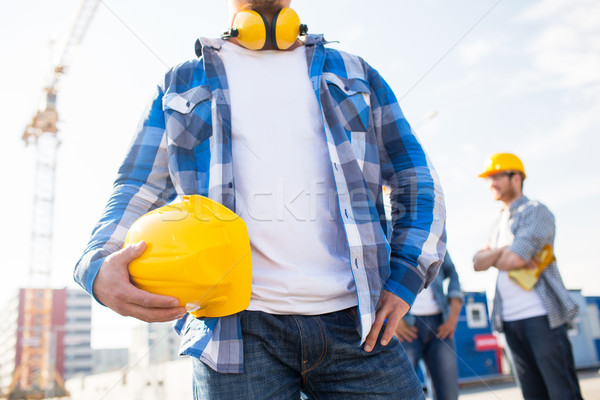 Stock photo: close up of builder holding hardhat at building