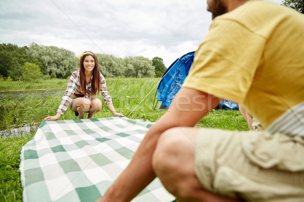 happy couple laying picnic blanket at campsite Stock photo © dolgachov