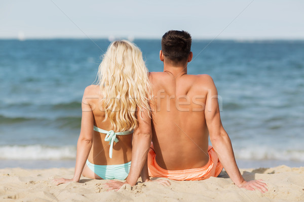 happy couple in swimwear sitting on summer beach Stock photo © dolgachov