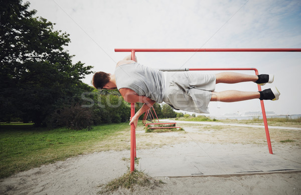 young man exercising on parallel bars outdoors Stock photo © dolgachov