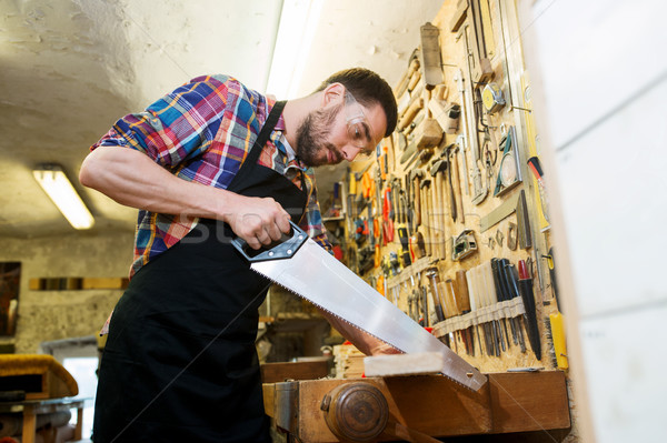 carpenter working with saw and wood at workshop Stock photo © dolgachov