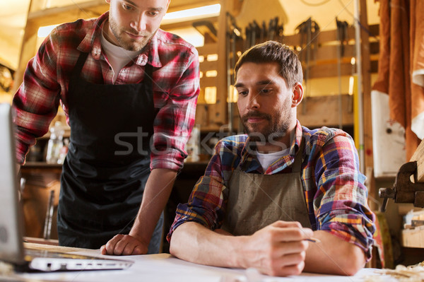 carpenters with laptop and blueprint at workshop Stock photo © dolgachov