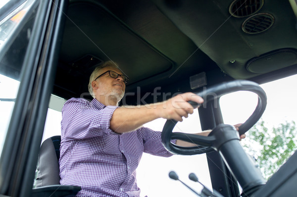 senior man driving tractor at farm Stock photo © dolgachov