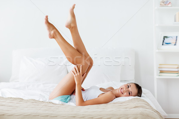 happy woman lying on bed and touching legs at home Stock photo © dolgachov